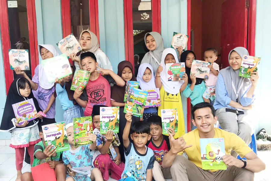Anak-anak dan relawan dengan buku bacaan